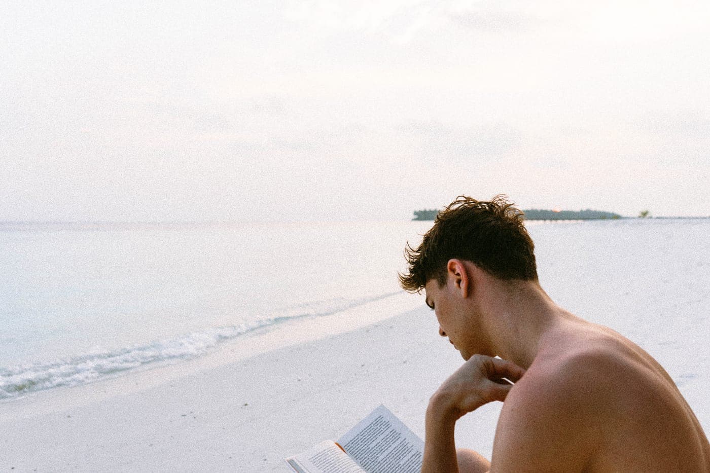A book being read on a beach in the sun