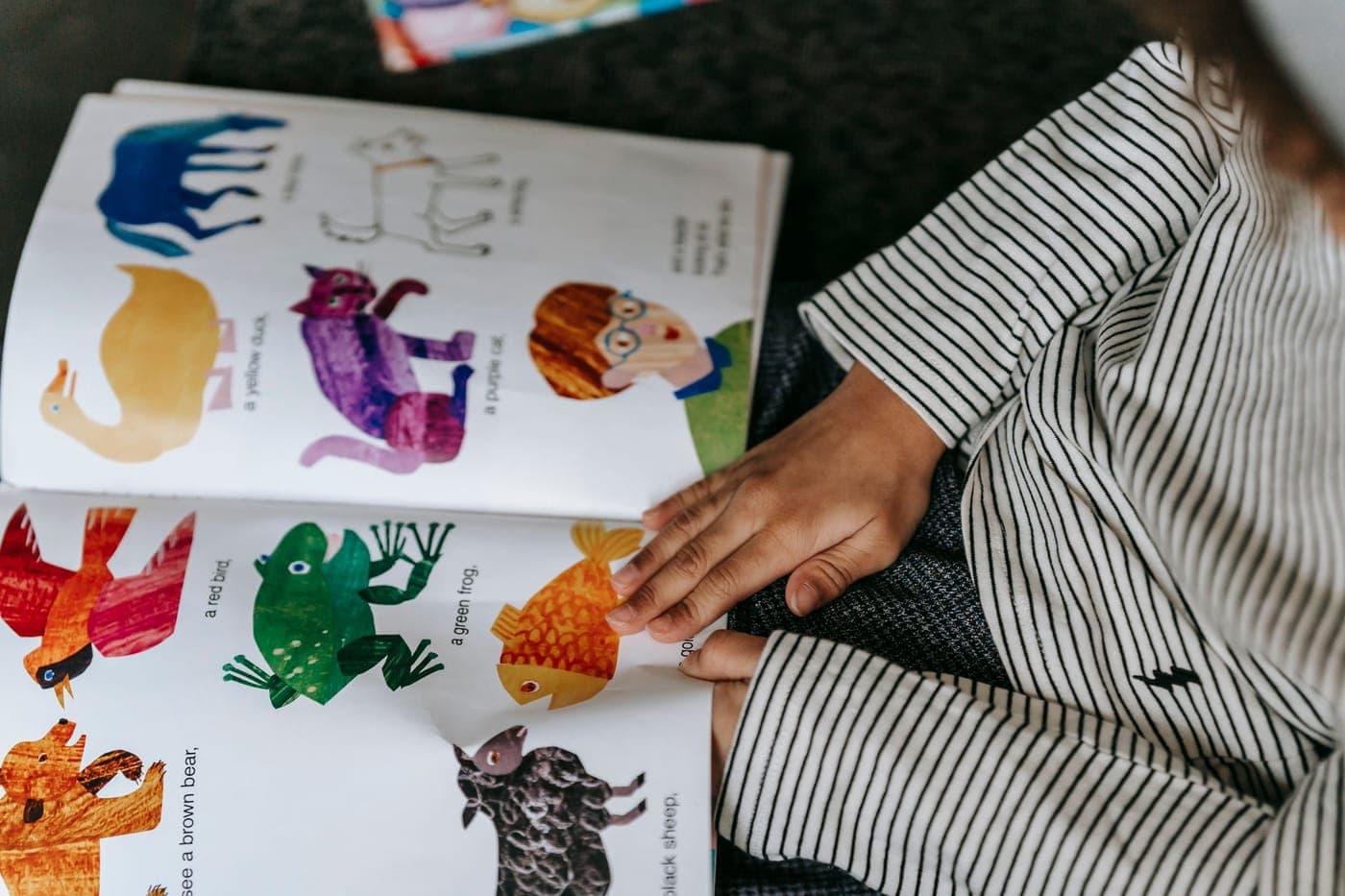 A child listening with headphones while looking at a book