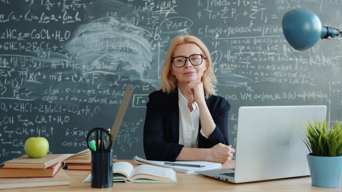 A teacher's desk with books in a classroom