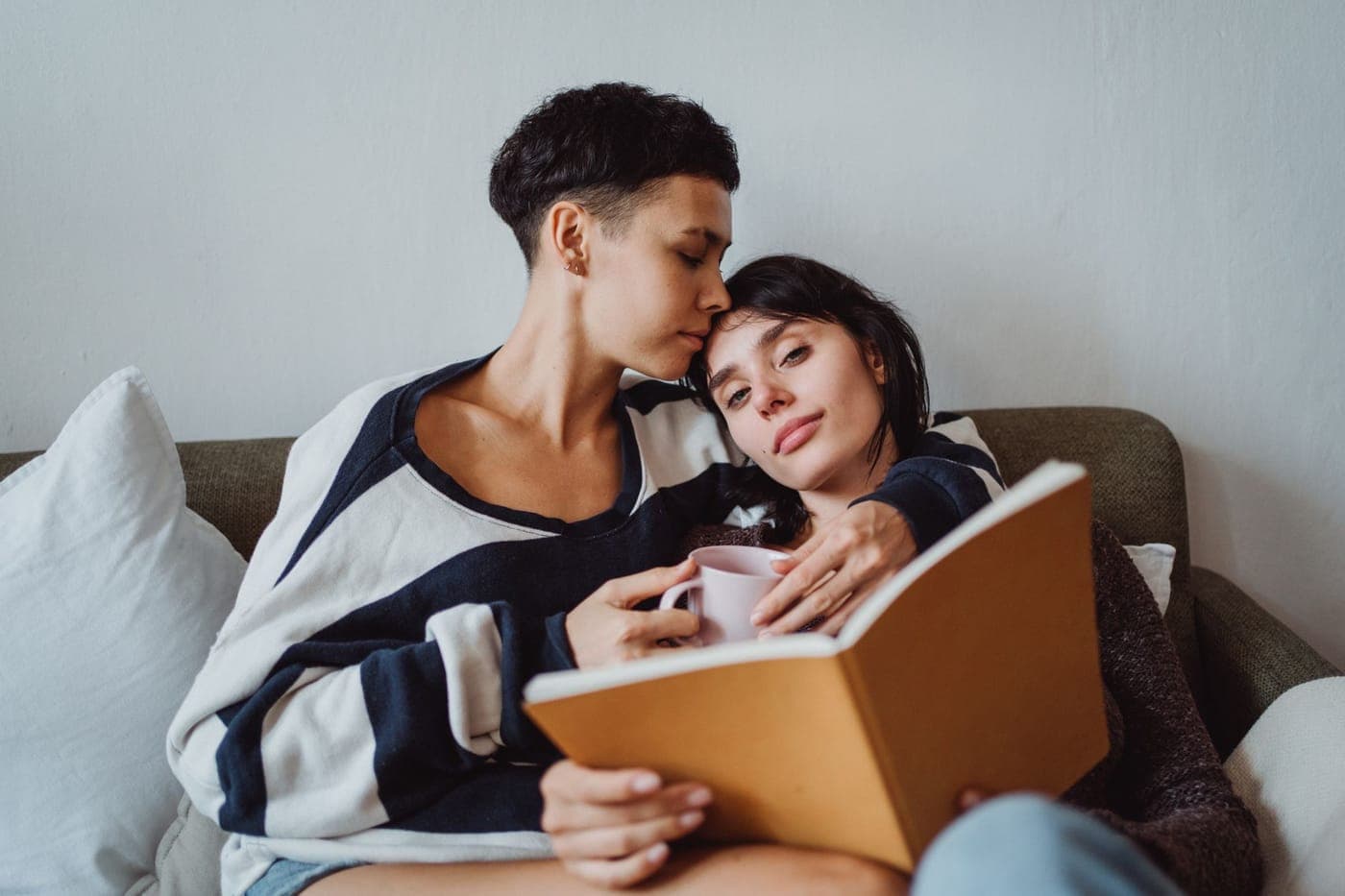 Two people reading together on a sofa