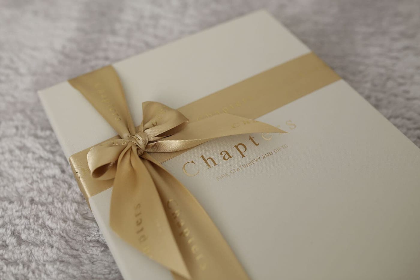 A wrapped gift tied with ribbon next to a stack of books