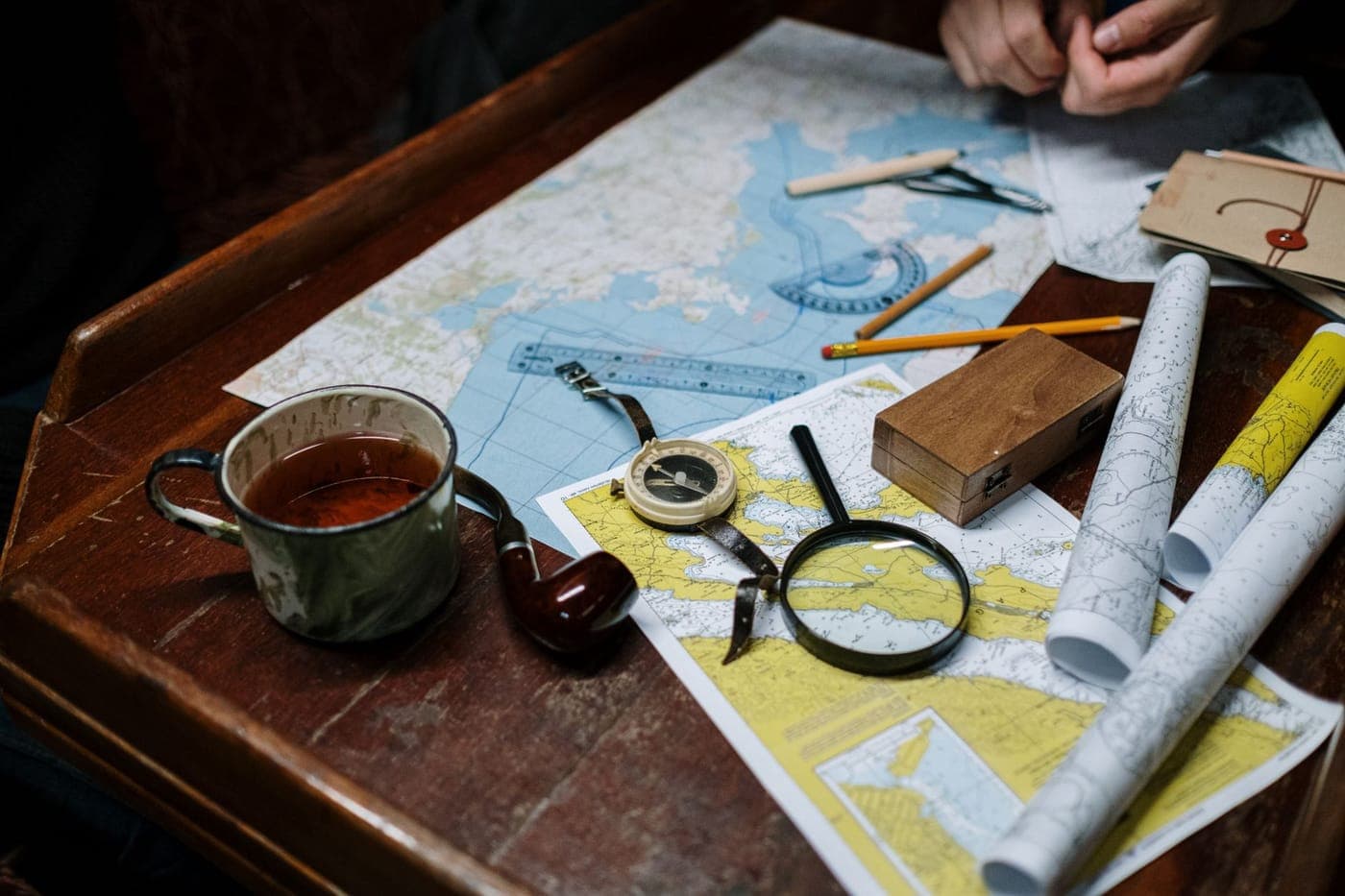An old map and a brass compass on a wooden table
