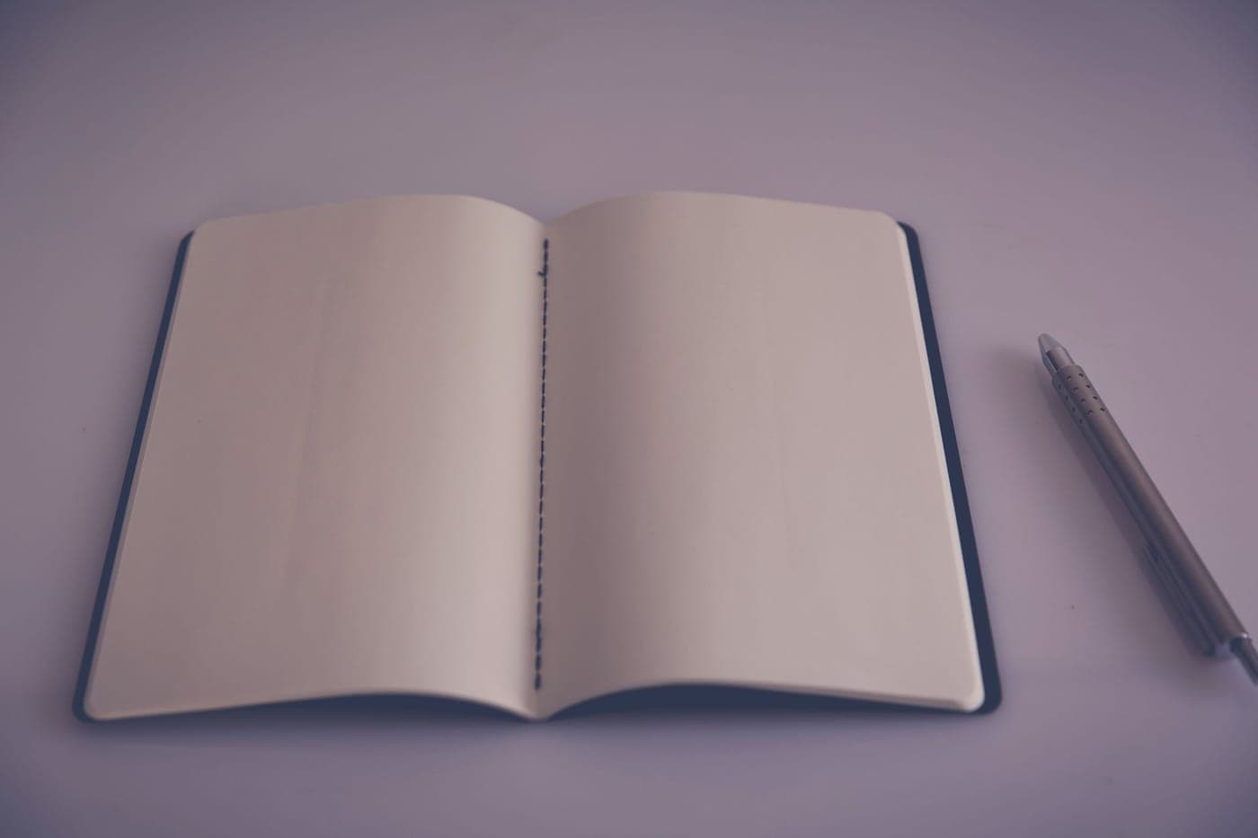 A notebook and pen on a plain wooden desk