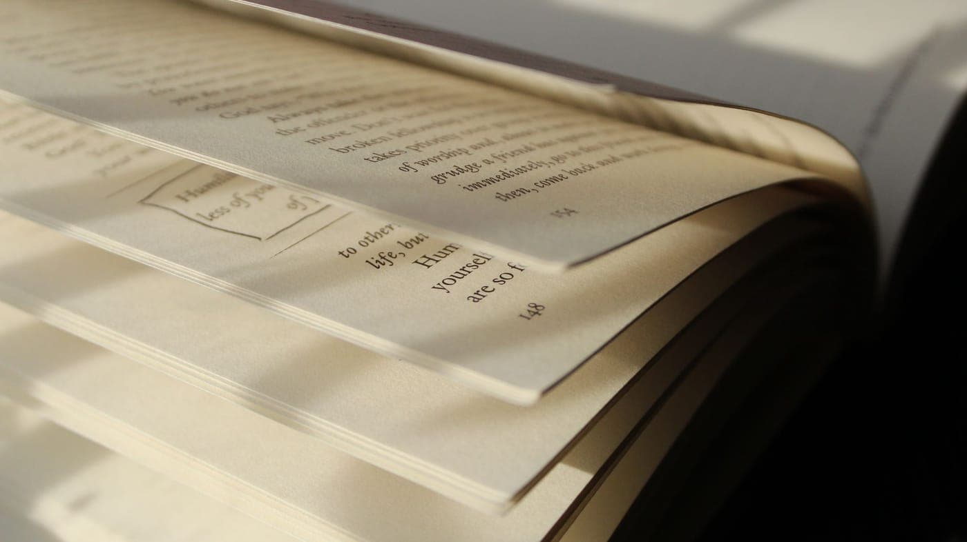 An open printed book beside an e-reader