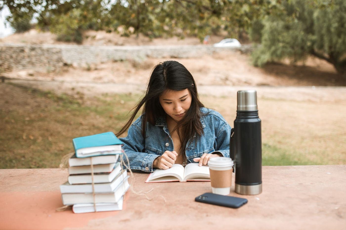 A teenager reading a book outdoors